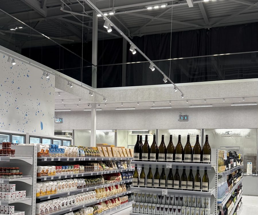 Стелажі з вином і бакалією під трековими прожекторами в Egersund Seafood