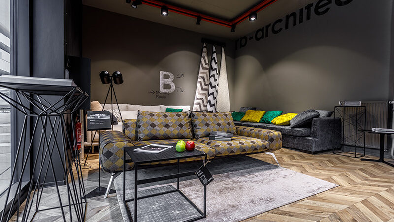 Patterned sofa and corner sofa with cushions in the Blanche showroom in Warsaw under track spotlights