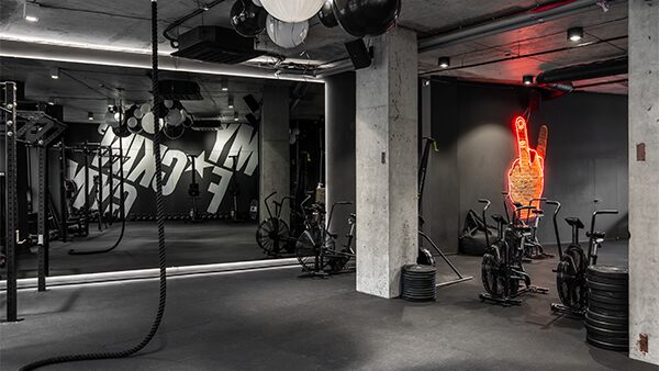 Тренувальна зона My F+ckin’ Gym у Києві з бетонними колонами, канатом і неоновою вивіскою