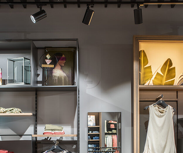TECHNIK TRL100ND track luminaires above shelves and a clothing display in the LERROS shop