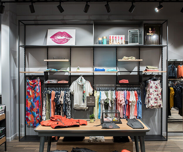 Wall with a clothing collection and a display table in the LERROS shop in Kyiv under track luminaires