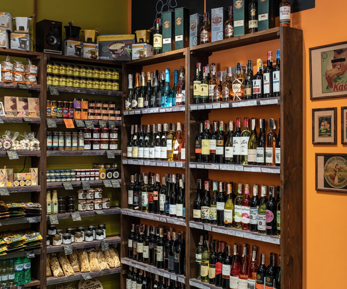 Wine and grocery racks by an orange wall in the Cheese Kingdom shop