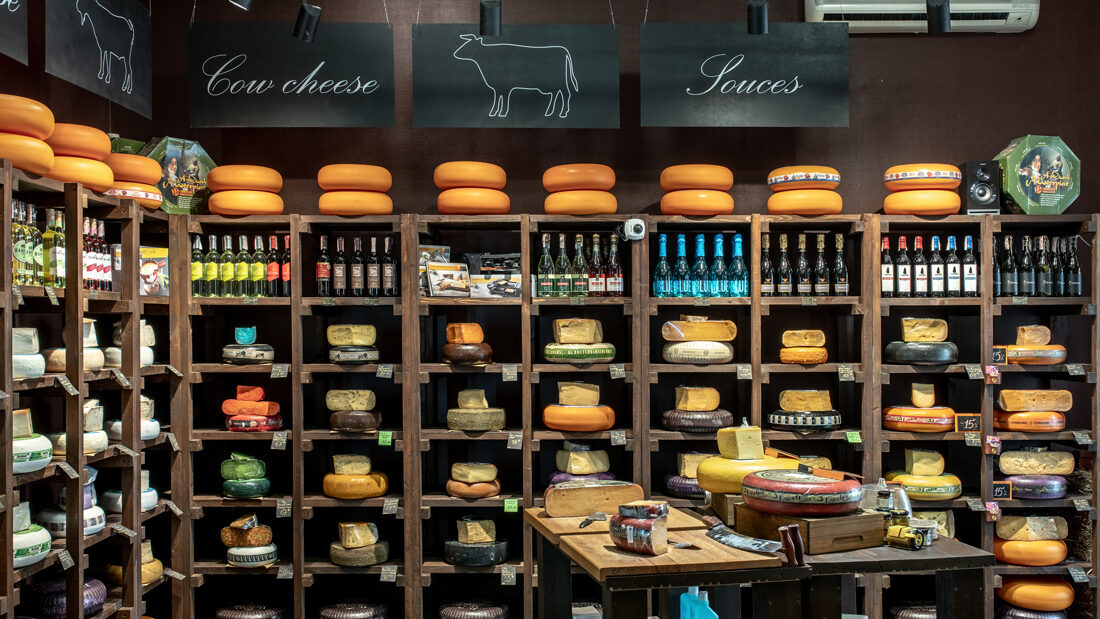 Wooden racks with cheese wheels and wine in the Cheese Kingdom shop, Kyiv