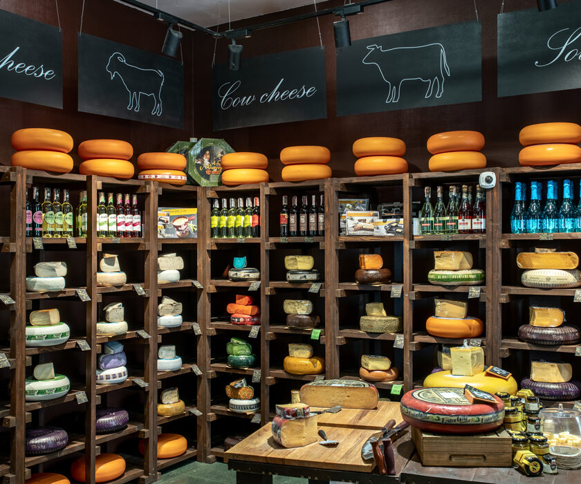 Corner rack with cheese and wine under track spotlights in the Cheese Kingdom shop