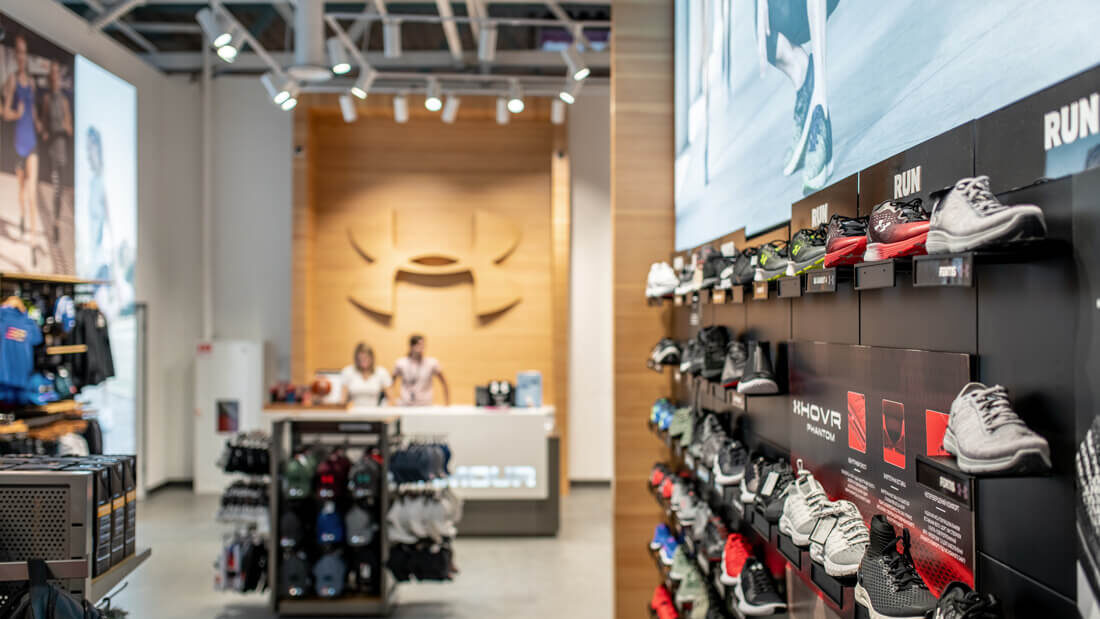 Стена с беговой обувью и касса с логотипом в магазине Under Armour, Lavina Mall