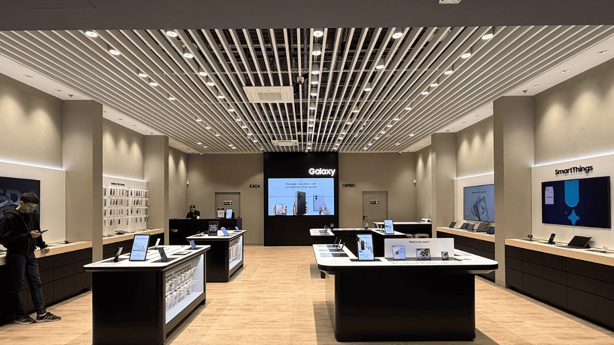 Demo tables with smartphones under SHOOTER-L track spotlights in the Samsung store